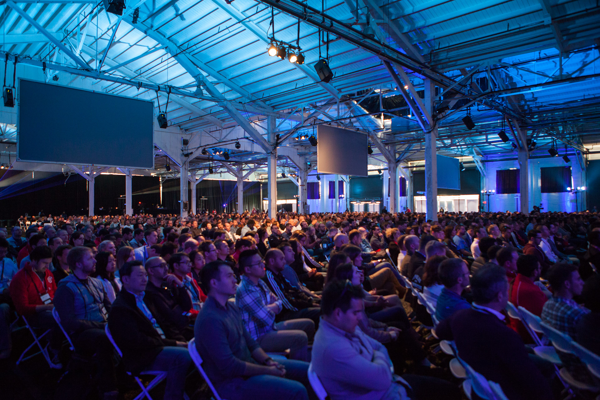 Packed audience in industrial warehouse venue with blue lighting